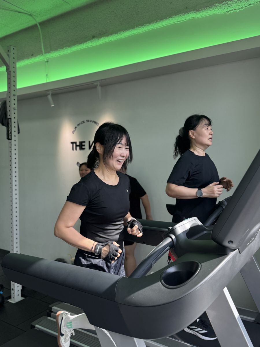 초록 조명 아래 트레드밀에서 웃으며 달리는 더비바 회원들